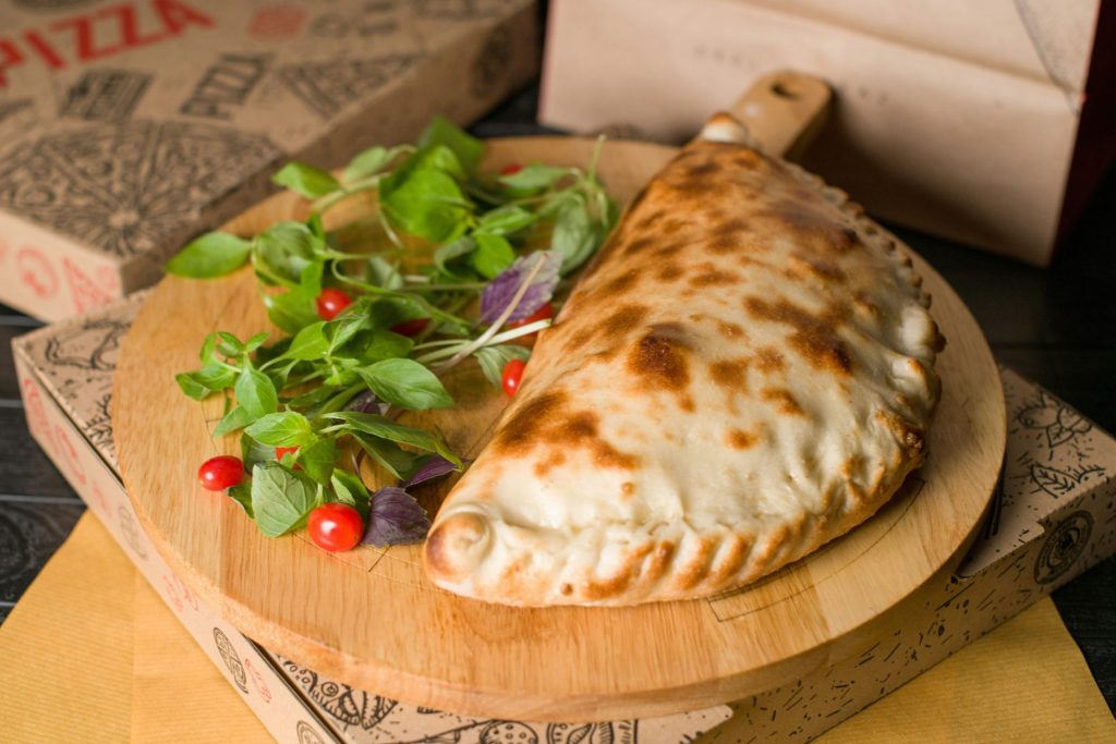 Eine leckere Calzone liegt auf einem Holzbrett.