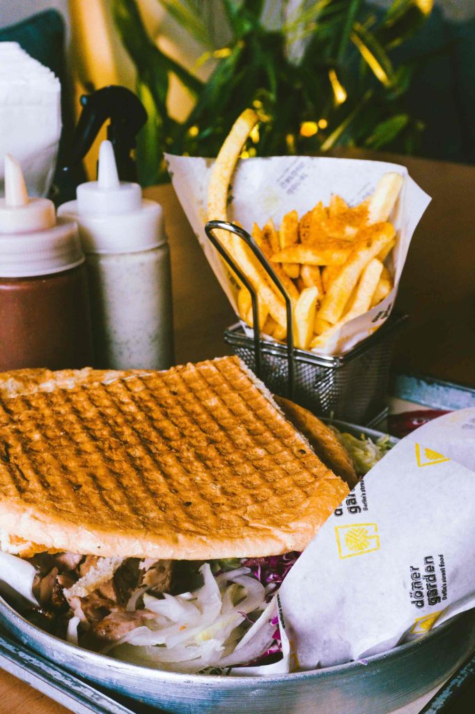Ein Waffelsandwich und Pommes Frites auf einem Tablett.