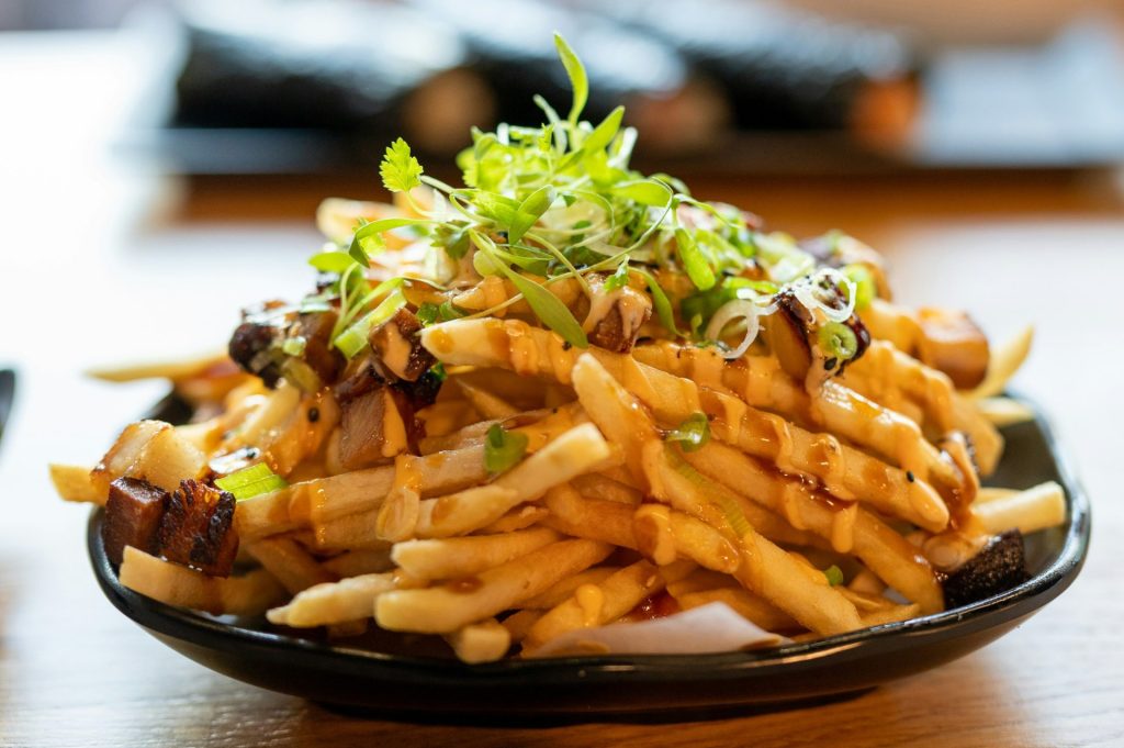 Ein Teller Pommes frites mit Soße und Sprossen